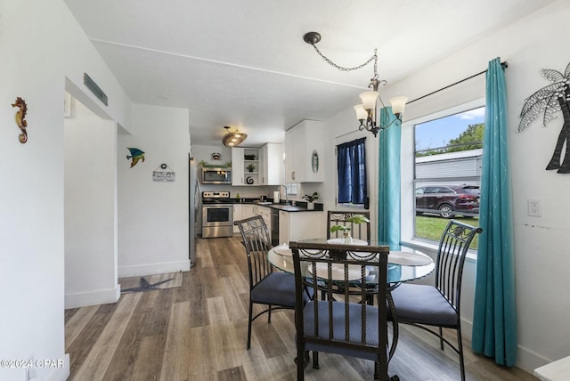 dining space with a chandelier, wood-type flooring, and sink