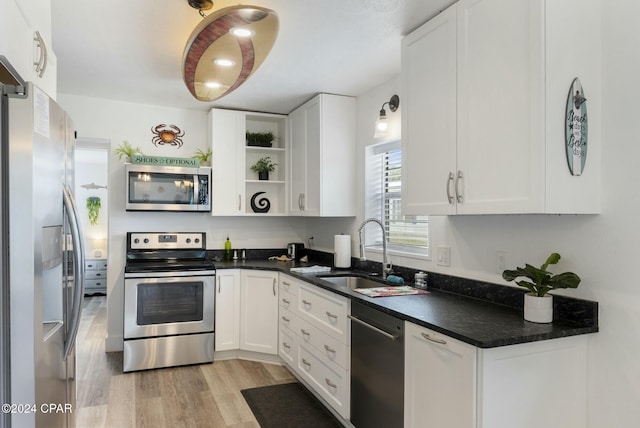 kitchen with white cabinetry, sink, appliances with stainless steel finishes, and light hardwood / wood-style flooring