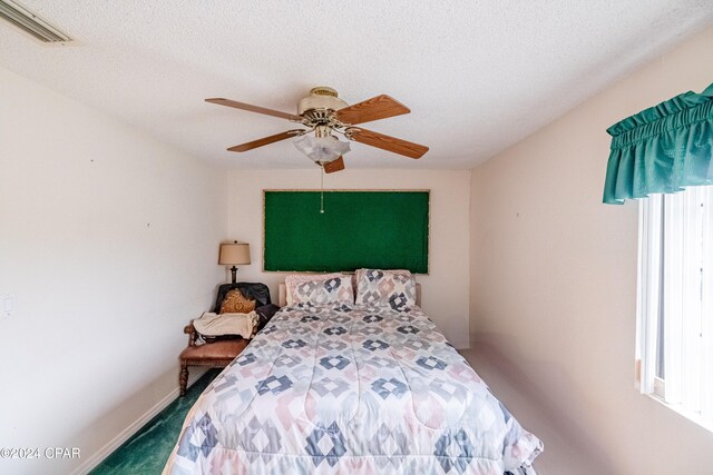 carpeted bedroom featuring ceiling fan, a textured ceiling, and multiple windows