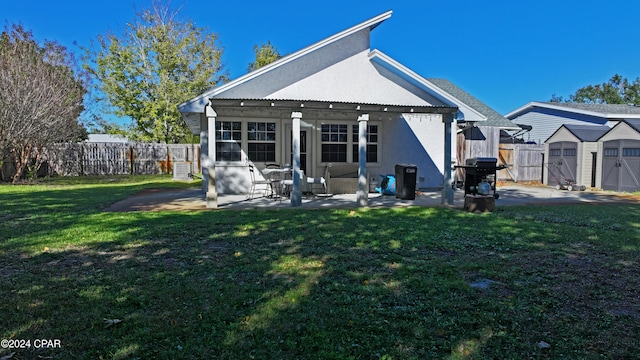 rear view of house featuring a patio area, a yard, and a storage unit