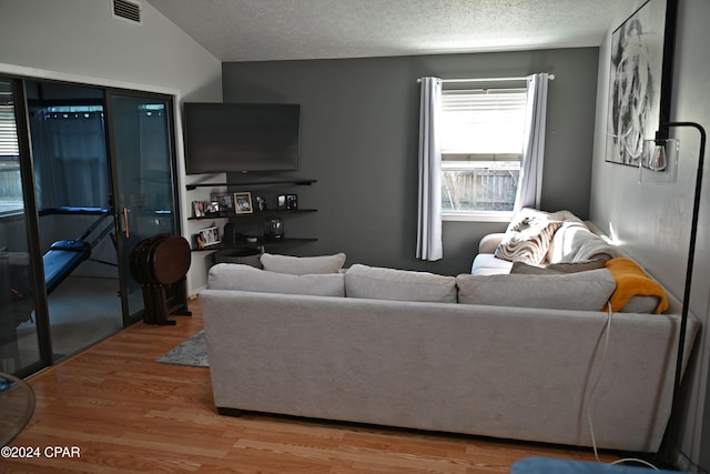 living room with wood-type flooring, a textured ceiling, and vaulted ceiling