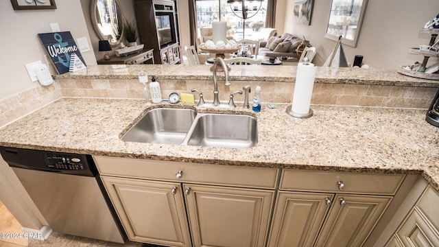 kitchen featuring light stone countertops, stainless steel dishwasher, a healthy amount of sunlight, and sink