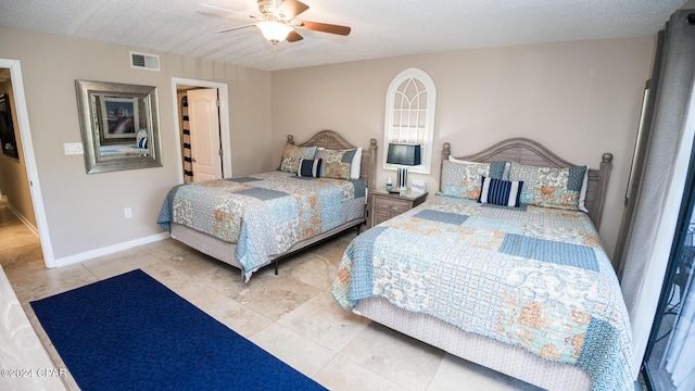 tiled bedroom with ceiling fan and a textured ceiling