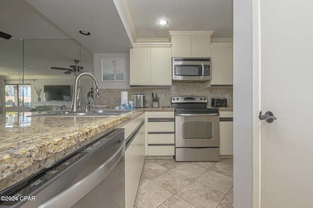 kitchen featuring sink, ornamental molding, appliances with stainless steel finishes, light stone countertops, and decorative backsplash