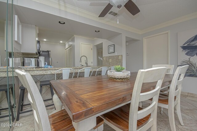 dining space featuring ornamental molding, sink, and ceiling fan