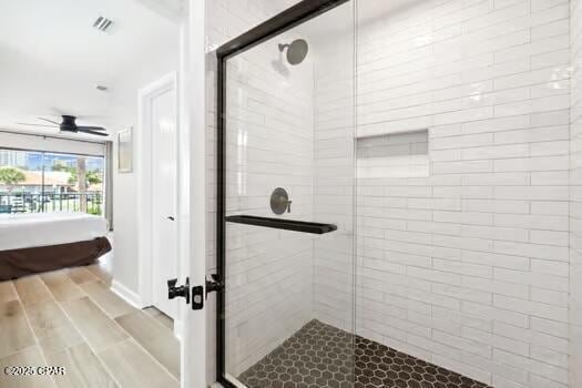 bathroom with hardwood / wood-style flooring, a shower with door, and ceiling fan