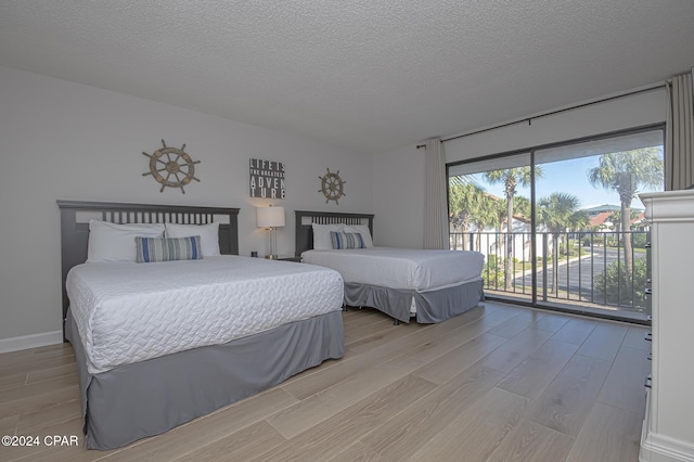 bedroom featuring access to exterior, light hardwood / wood-style floors, and a textured ceiling