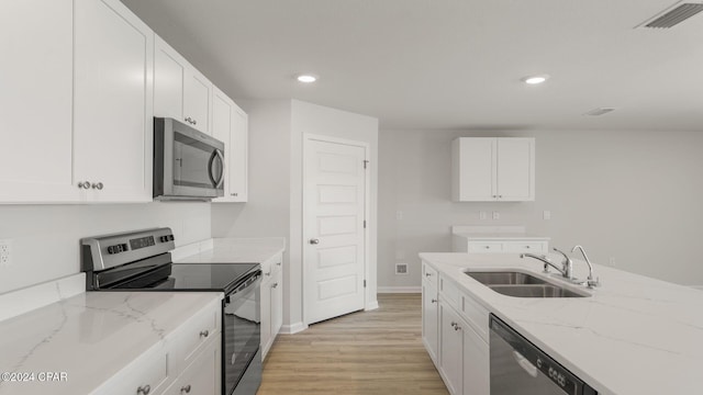 kitchen with sink, stainless steel appliances, light stone counters, white cabinets, and light wood-type flooring