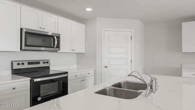 kitchen featuring appliances with stainless steel finishes, white cabinetry, and sink