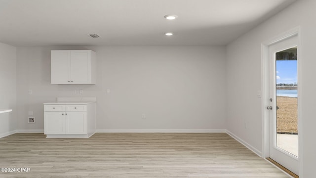 empty room with a wealth of natural light, a water view, and light hardwood / wood-style floors