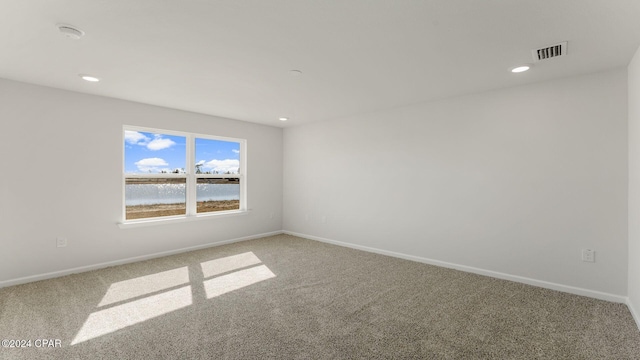 carpeted spare room with a water view