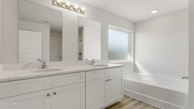 bathroom with a bathing tub, vanity, and wood-type flooring