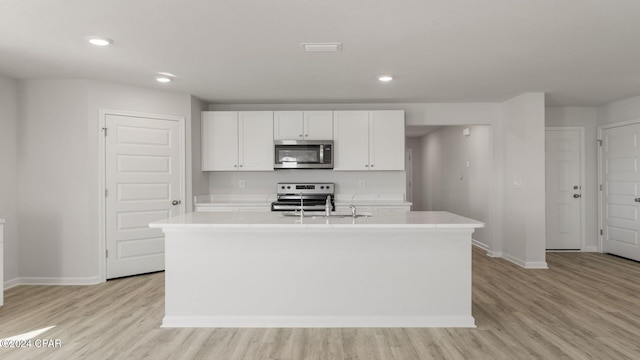 kitchen with stainless steel appliances, sink, a center island with sink, light hardwood / wood-style flooring, and white cabinetry