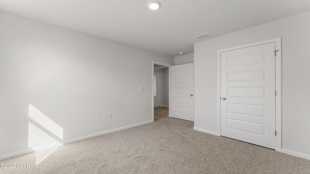 unfurnished bedroom featuring light carpet and a closet