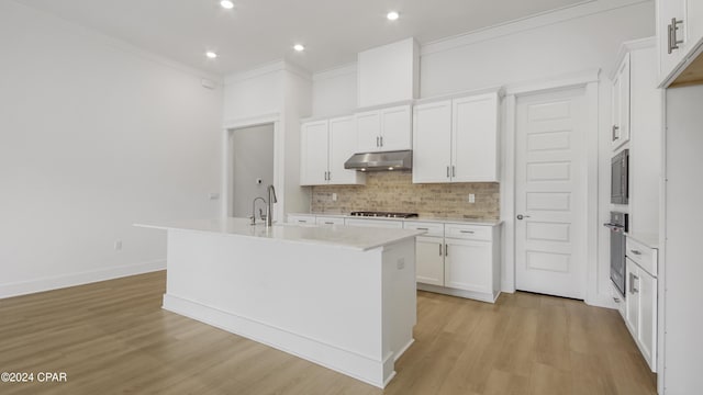 kitchen featuring crown molding, light wood-type flooring, an island with sink, appliances with stainless steel finishes, and white cabinetry