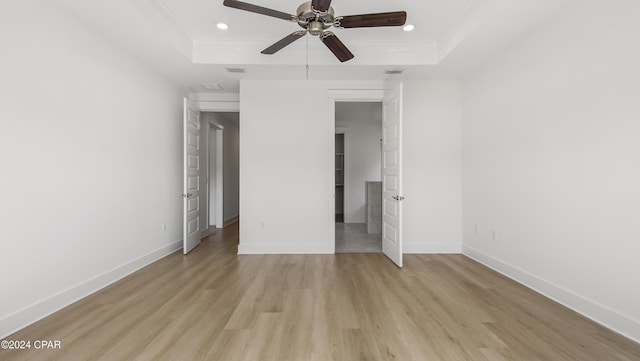 unfurnished bedroom featuring a tray ceiling, light hardwood / wood-style flooring, and ceiling fan