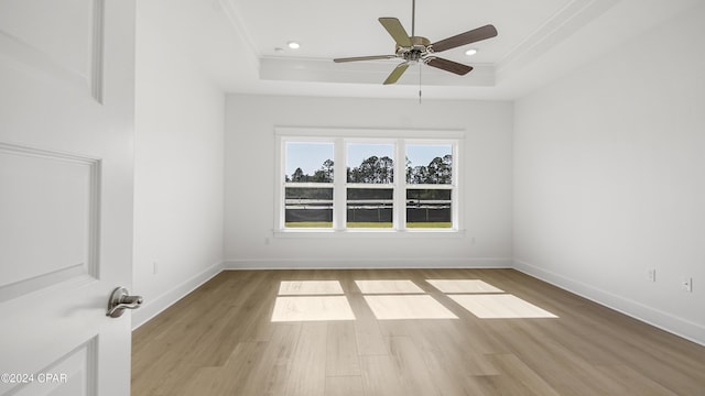 unfurnished room featuring light wood-type flooring, a tray ceiling, and ceiling fan