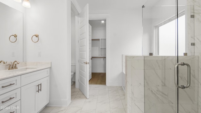 bathroom featuring a shower with door, vanity, and toilet