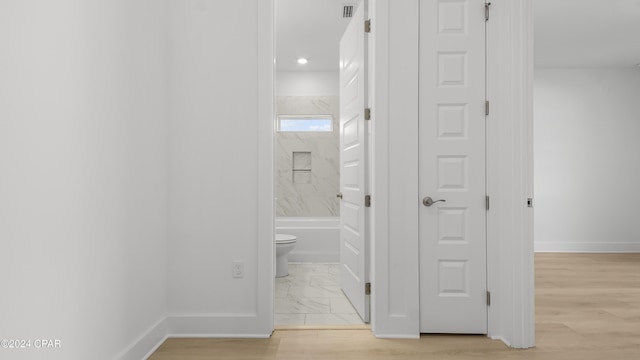 bathroom featuring toilet, wood-type flooring, and tiled shower / bath