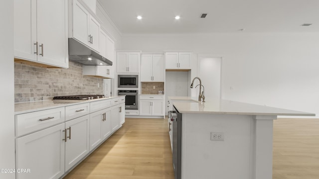 kitchen with a kitchen island with sink, sink, white cabinets, and appliances with stainless steel finishes