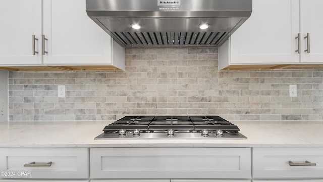 kitchen with wall chimney exhaust hood, white cabinetry, stainless steel gas cooktop, and tasteful backsplash