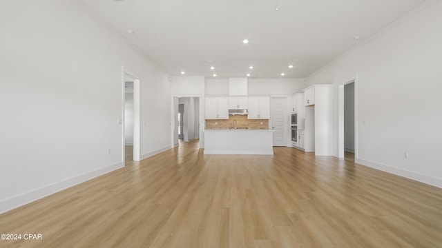 unfurnished living room featuring ornamental molding, sink, and light hardwood / wood-style flooring