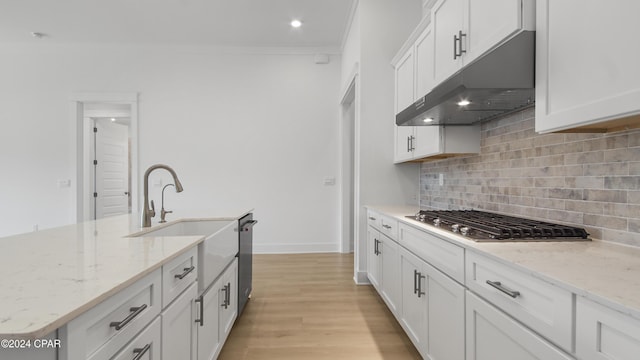 kitchen with white cabinets, light stone countertops, light wood-type flooring, and stainless steel gas cooktop