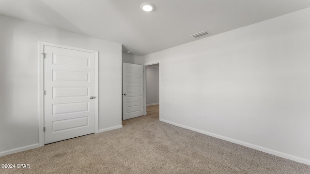 unfurnished bedroom featuring light carpet and a closet