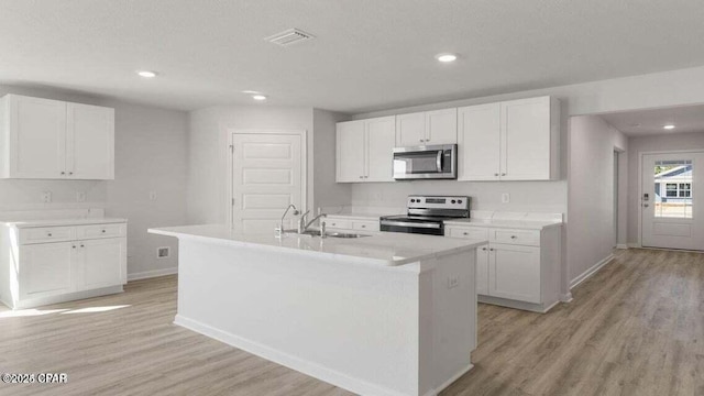 kitchen with an island with sink, appliances with stainless steel finishes, and white cabinets