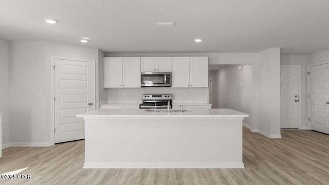 kitchen featuring sink, a center island with sink, stainless steel appliances, light hardwood / wood-style floors, and white cabinets