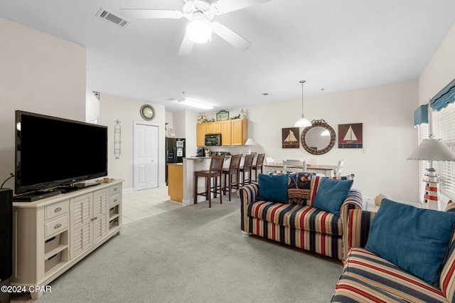 living room with light colored carpet, visible vents, ceiling fan, and light tile patterned floors