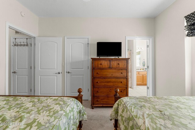 bedroom featuring light carpet, ensuite bath, and a closet