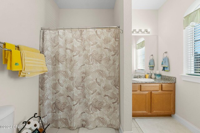 bathroom with toilet, vanity, and tile patterned floors