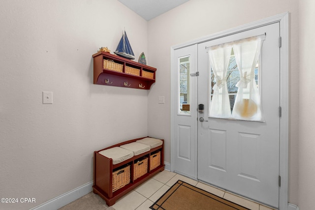 doorway with light tile patterned floors and baseboards