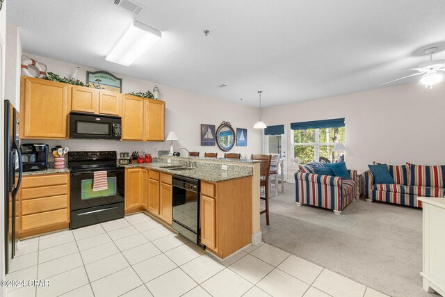 kitchen with sink, light stone counters, kitchen peninsula, light carpet, and black appliances