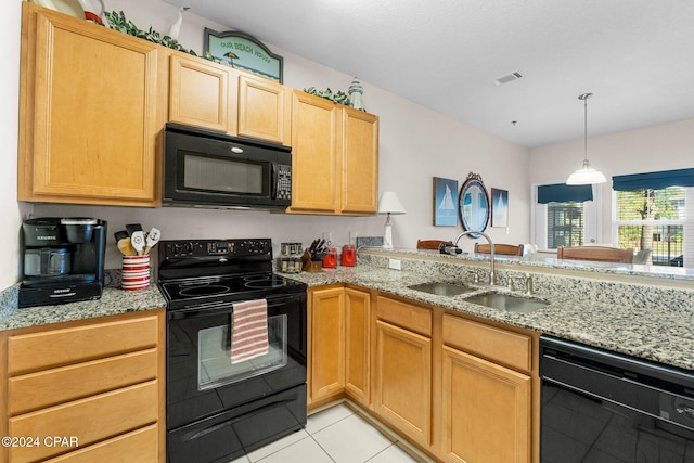 kitchen featuring light stone counters, a peninsula, a sink, visible vents, and black appliances