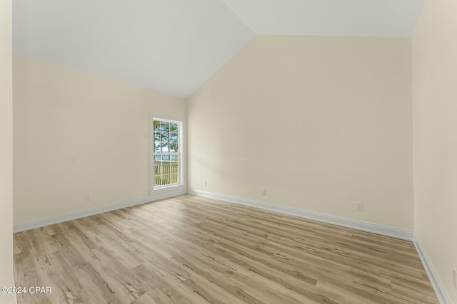 unfurnished room with lofted ceiling and light wood-type flooring