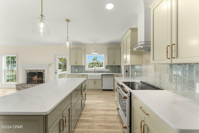 kitchen featuring appliances with stainless steel finishes, light wood-type flooring, wall chimney exhaust hood, pendant lighting, and a kitchen island