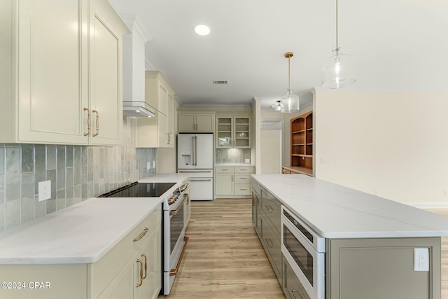 kitchen with light stone countertops, white appliances, pendant lighting, a center island, and light hardwood / wood-style floors