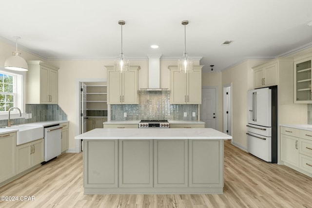 kitchen featuring a center island, sink, wall chimney range hood, light hardwood / wood-style flooring, and white appliances