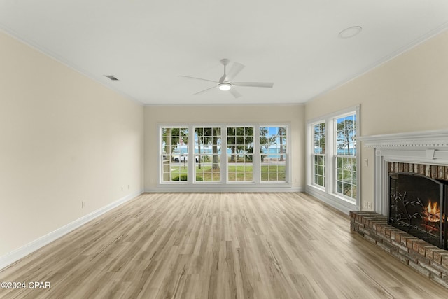 unfurnished living room with a fireplace, plenty of natural light, ornamental molding, and light wood-type flooring