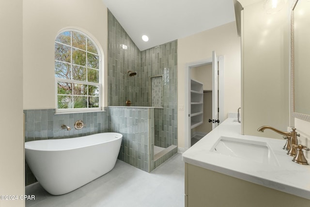 bathroom featuring vanity, separate shower and tub, lofted ceiling, and tile walls