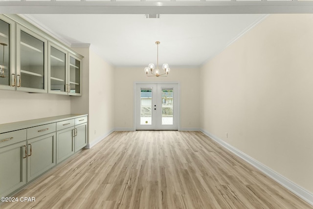 unfurnished dining area featuring a chandelier, ornamental molding, french doors, and light hardwood / wood-style flooring