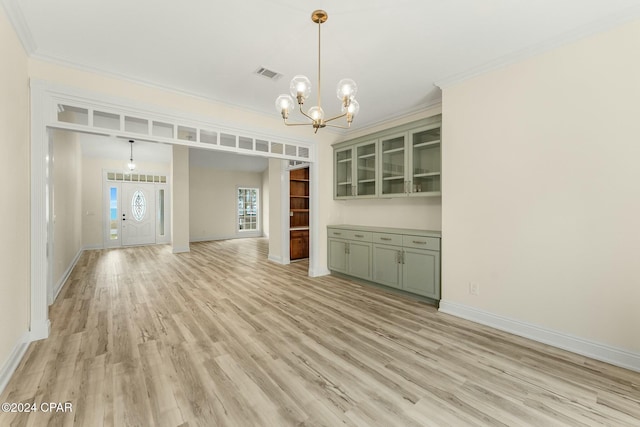 unfurnished living room with a chandelier, crown molding, and light hardwood / wood-style flooring