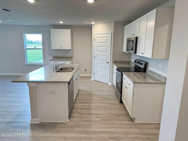 kitchen with white cabinets, sink, light wood-type flooring, an island with sink, and stainless steel appliances