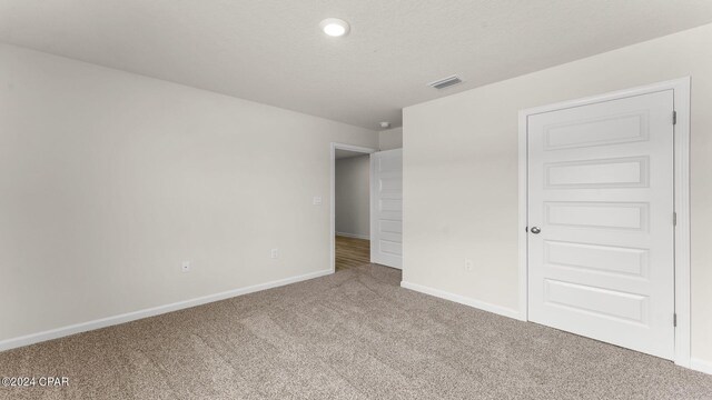 spare room featuring light carpet and a textured ceiling