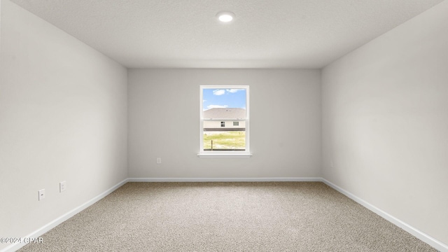 unfurnished room featuring carpet and a textured ceiling