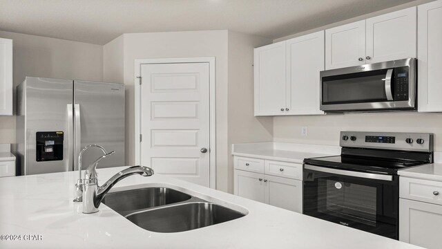 kitchen featuring appliances with stainless steel finishes, light wood-type flooring, a textured ceiling, sink, and white cabinetry