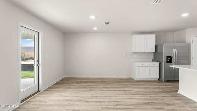 kitchen with plenty of natural light, stainless steel fridge, light wood-type flooring, and white cabinetry