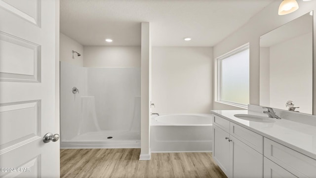 bathroom featuring plus walk in shower, vanity, and hardwood / wood-style flooring